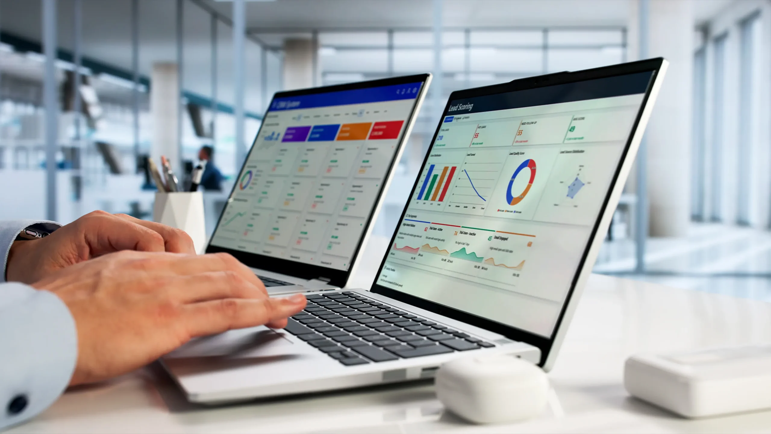 Two hands typing on a laptop. The screen shows various analytic tables for marketing.