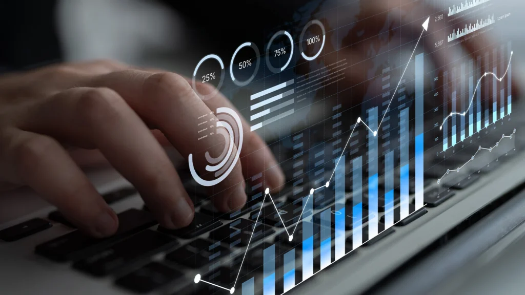 An image of illuminated metrics hovering above hands typing on a laptop keyboard.